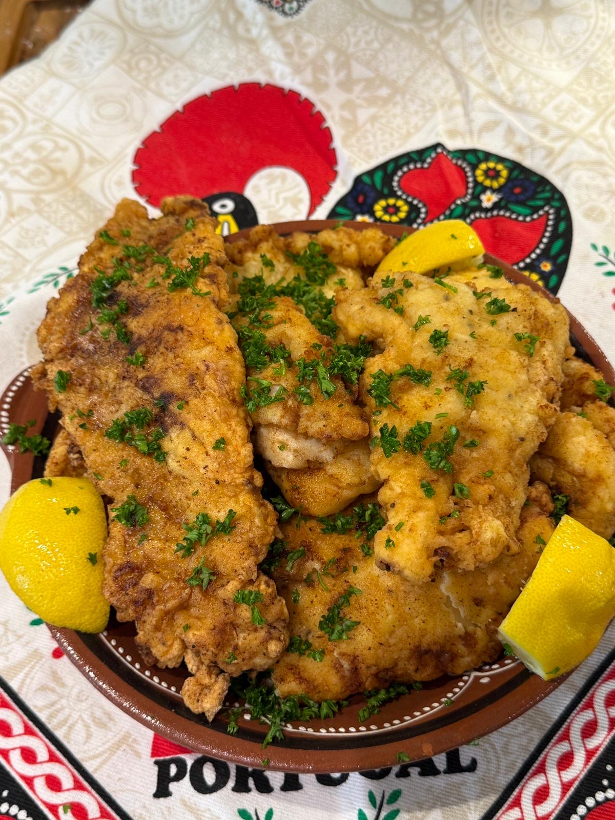 Filetes de Peixe on a plate with lemon wedges. 